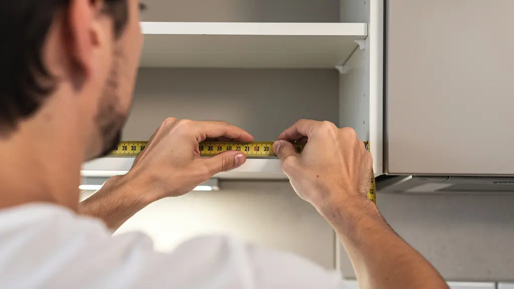 Personne mesurant une niche d'encastrement vide avec un mètre ruban